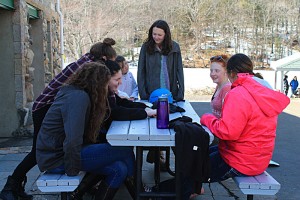 Group of teens around a picnic table in the winter talking.